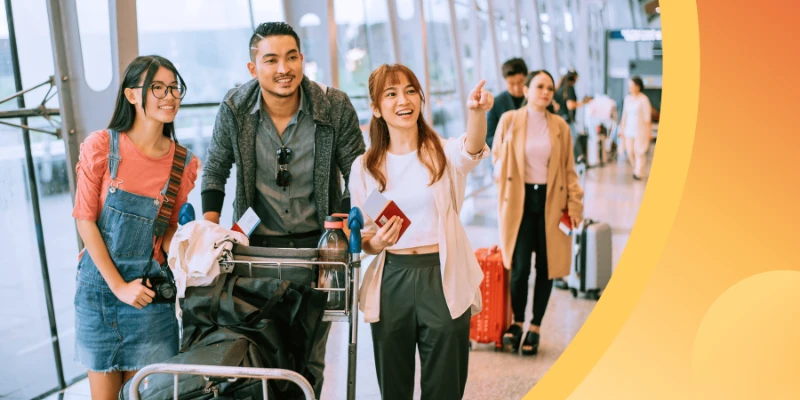 A group of smiling young international students with luggage and passports at a bright airport terminal, looking forward with excitement.