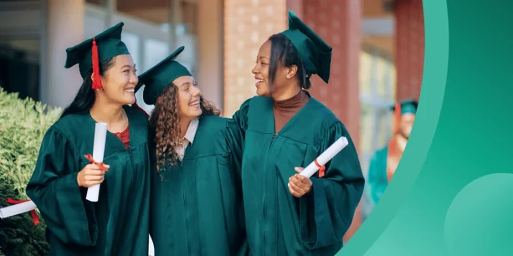Three diverse female graduates standing together outdoors in green caps and gowns, smiling and holding their diplomas.