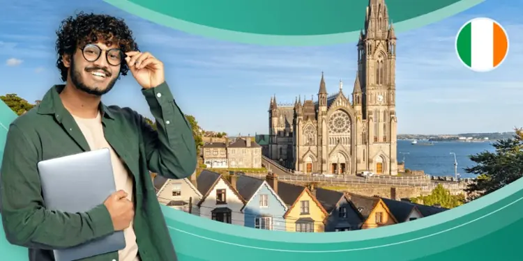 Male student holding a laptop with St. Colman's Cathedral in Cobh, Ireland in the background